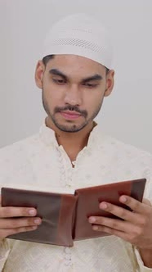 Man Reads Book Indoors, Wearing Knit Cap