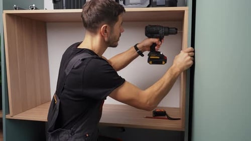 Man Drilling Hole in Cabinet Side Panel During Furniture Assembly