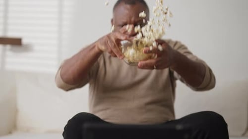 Mature Man Watching Scary Movie in Evening and Fearing Throwing Popcorn Up Shock and Fear Horror