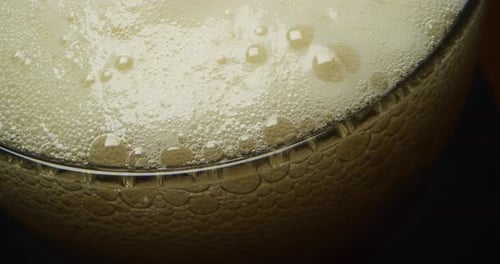 Close up of some beer in a glass with a nice white foam on a black background. Concept: food and d