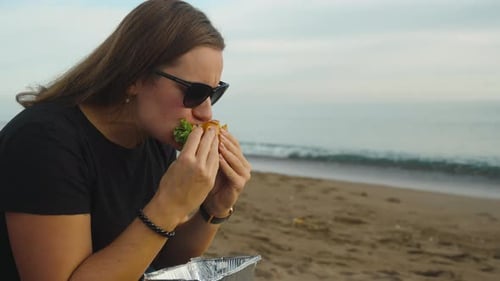 Woman Eating Sandwich on the Beach
