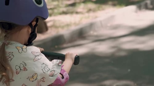 Girl 3 Years Old Rides a Scooter in Protective Clothing