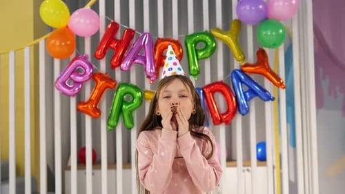 Child Celebrates Birthday with Balloons and Party Hat