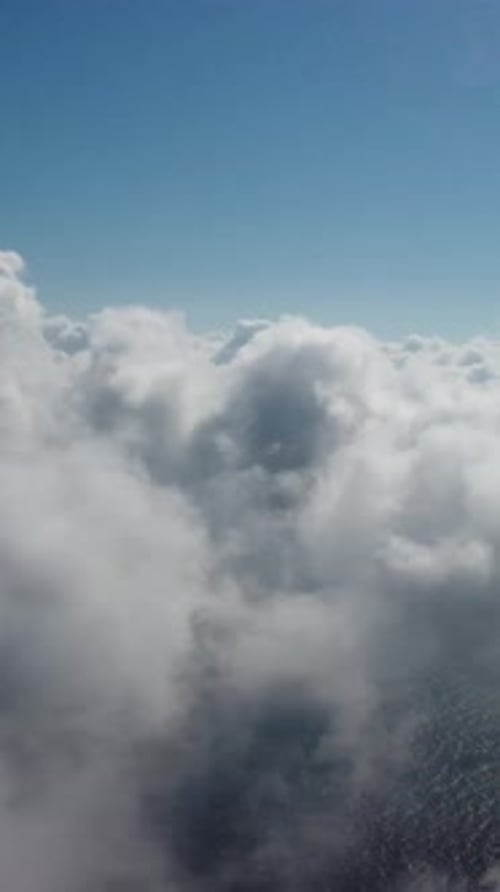 Drohne fliegt über neblige und flauschige Wolken, vertikale Luftaufnahme, blauer Himmel, Sonne und Meeresnebel, abstrakt