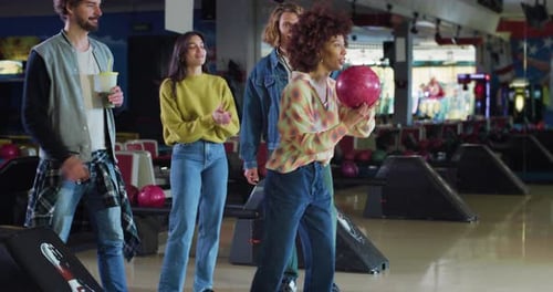 Filmaufnahme einer glücklichen jungen afrikanischen Bowlerin, die einen Strike-Ball wirft und dabei den Sieg jubelt