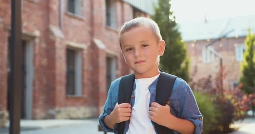 Close-up of a small schoolboy in a shirt with a backpack. Close up portrait of happy cute male