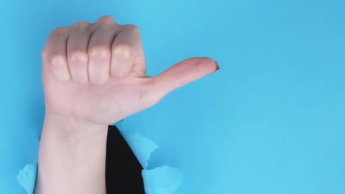 Hand Showing Thumbs Up Through Ripped Paper