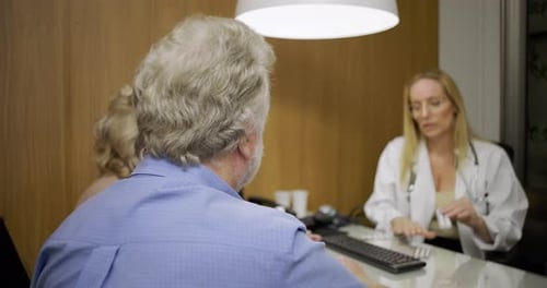 Mature Couple Consulting Doctor in Office About Medication