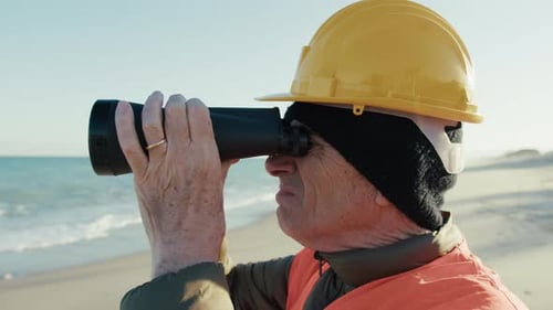 Ingeniero usa binoculares para observar algo en el océano