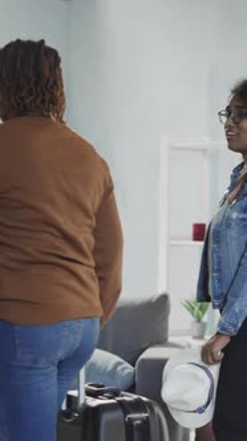 Amigas com mala saem da sala olhando em volta