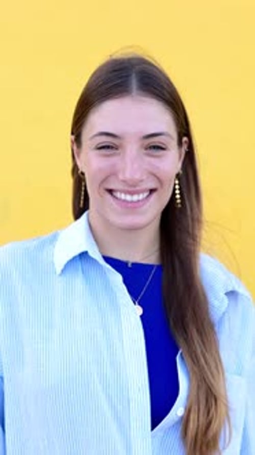 Smiling Woman with Long Hair in Front of Yellow Wall