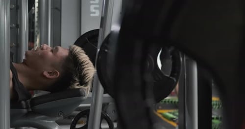 Man Weightlifting on Bench Press in Gym