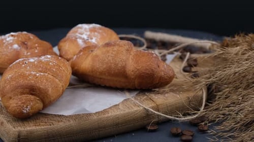 Golden Croissants Sprinkled with Sugar on Rustic Board