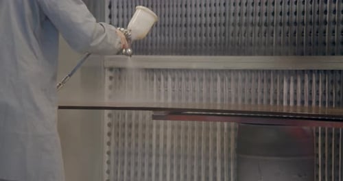 Slow motion close up of carpenter spray painting a cabinet