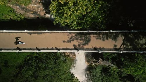 Man Walking On Bridge Above Waterfall Top View