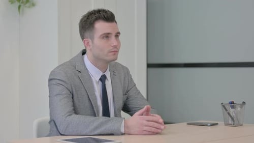 Pensive Young Businessman Thinking while Sitting at Work