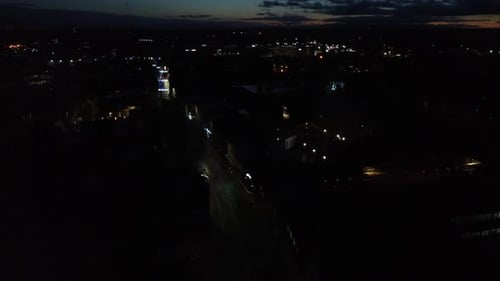 Aerial view quiet street illuminated houses urban weekend town at night slow descending shot