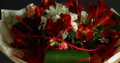 Zoomed in detailed a large bouquet of red and white flowers and green decorative elements in a glass