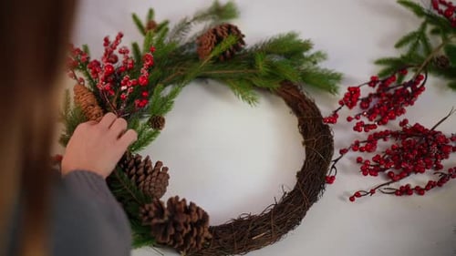 High Angle View Handmade Christmas Wreath with Female Hand Attaching Red Snowy Berries