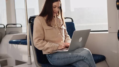 Young Woman Using Laptop on Public Transportation