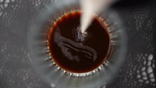 Milk Being Poured into Glass of Coffee