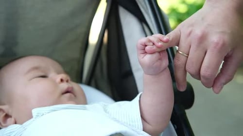 Baby Grabs Finger Lying in Stroller
