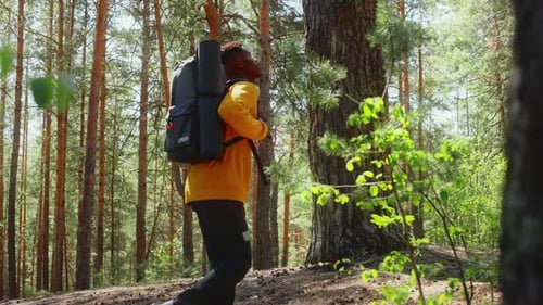 An African American Traveler with a Backpack Walks Through the Forest