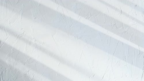 White Plaster Wall with Rough Texture and Subtle Shadows Across the Surface The Minimal Background