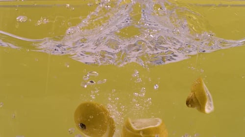 Sliced lemon falls in water and gets separated in super slow motion.
Highspeed shot of lemon slices