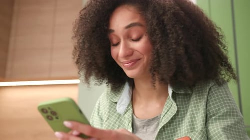 Woman Smiling and Using Mobile Phone Indoors