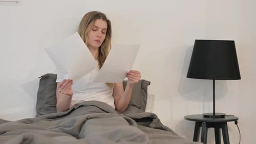 Woman Reading Papers in Bed in the Daytime