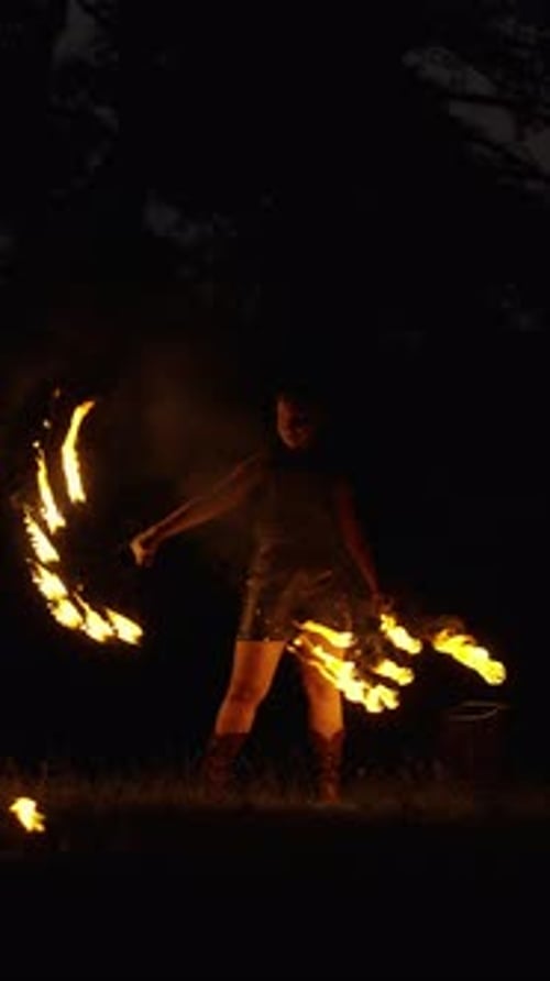 Nighttime Fire Performance with Dynamic Spinning Flames Creating Dramatic Light Trails Around a Lone