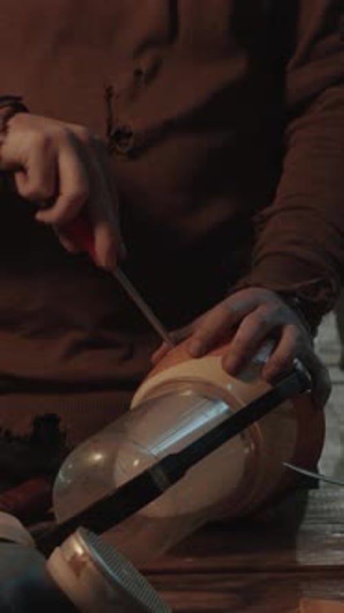 Man in Worn Sweater Fixing Lamp with Screwdriver