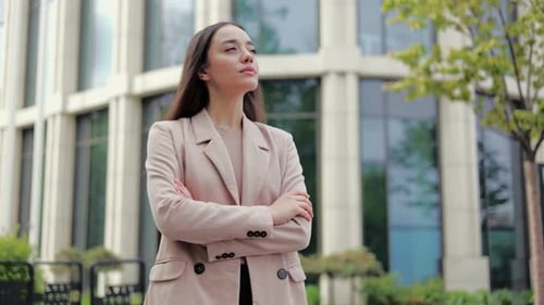 Thoughtful Female Rubbing Chin with Hand and Looking Up in City Square