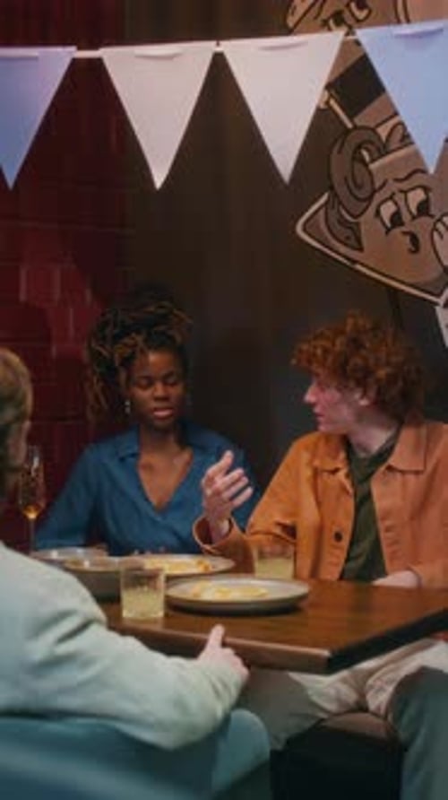 Group of Friends Chatting and Toasting at Table, Celebrating Birthday in bar