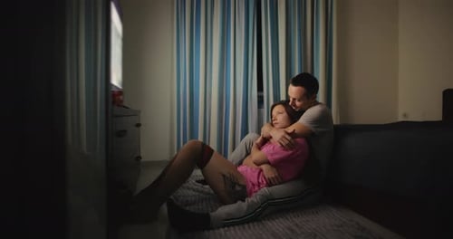 Loving Couple Cuddling and Watching Television at Night