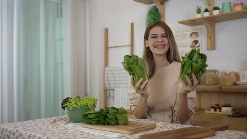 Smiling Woman Holds Fresh Green Lettuce at Home