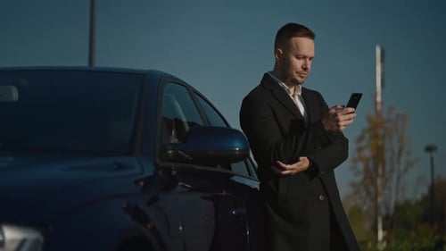 Man Uses Smartphone Next to Modern Car