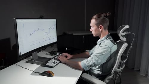 Young Adult Typing at Computer with Graph Display