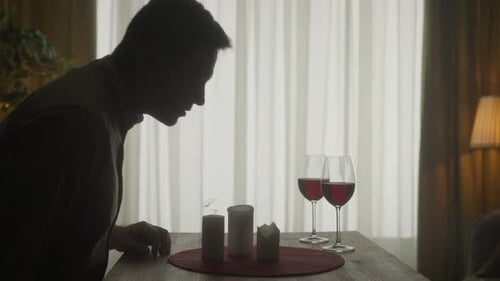 The Man Blows Out the Candles on the Table Next to the Glasses of Wine and Leaves the Room Dark