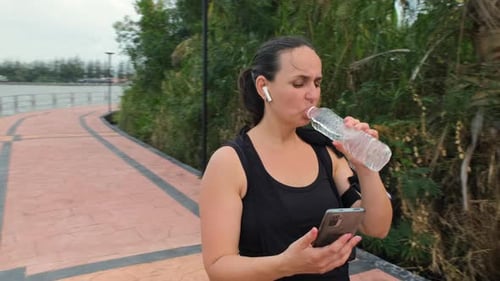Woman Walking with Phone and Water Bottle