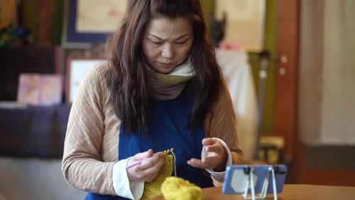 Woman Crocheting Yellow Yarn Craft at Home