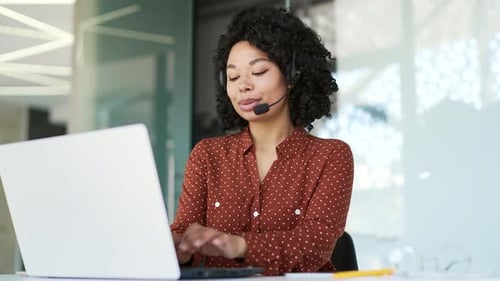 Woman Using Laptop and Headset at Workplace