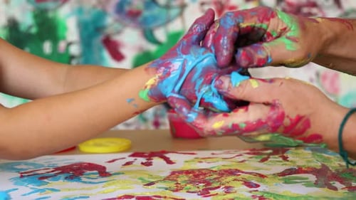 Adult holds child hands with blue and red paint on them. Stay home father concept