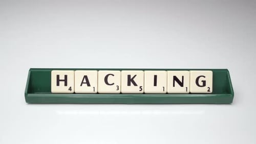 This is a close up shot of a caucasian woman placing a H to spell Hacking with Scrabble letters with