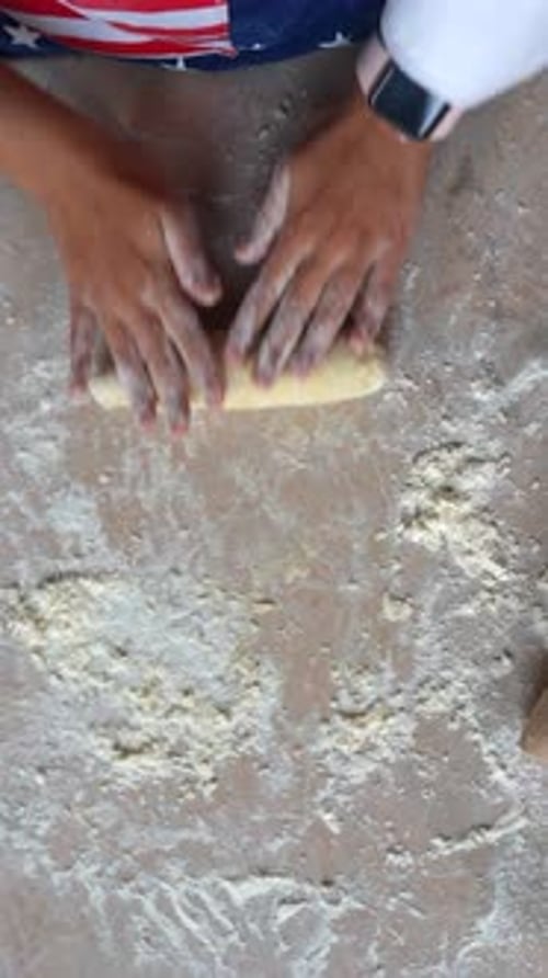 Young Housewife in an Apron Kneads Dough with Her Hands
