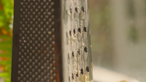 Descending Camera View of Grater After Grating Cheddar with Block of Rustic Cheese Resting on Plate