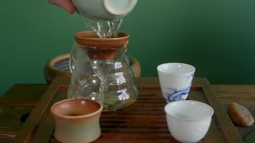 Hands of Tea Master Pouring Fresh Green Brewing Tea From Gaiwan to Glass Pot