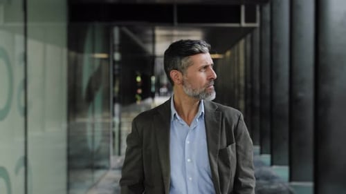 Elegant Spanish Businessman with Beard Walking in Modern Urban Office with Attitude and Confidence