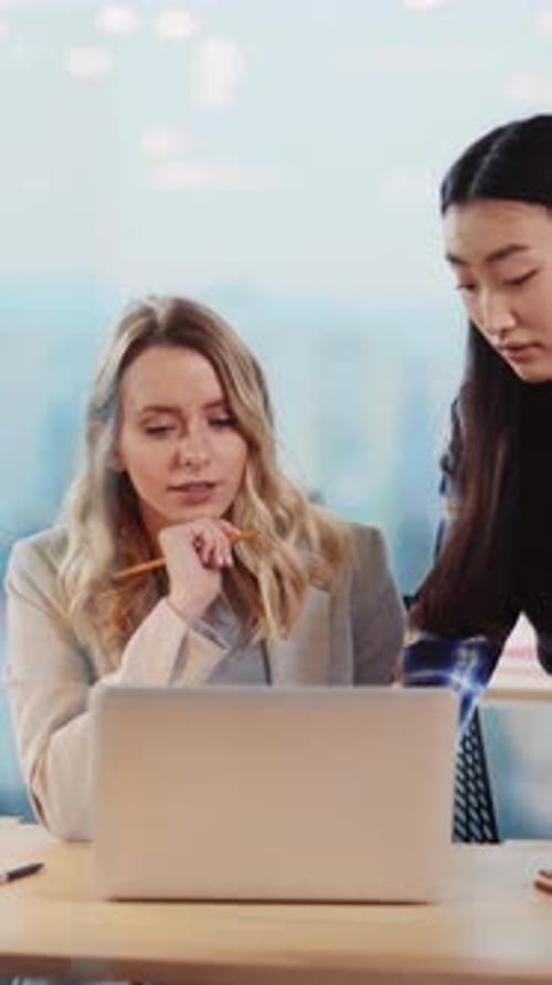 Two Women Working Together at Desk in Office